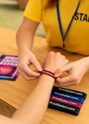 Event staff checking wristbands at a festival entrance under bright lighting.