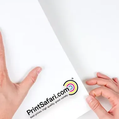 Person holding a large rectangular sticker with the PrintSafari.com logo, partially rolled out on a flat surface.