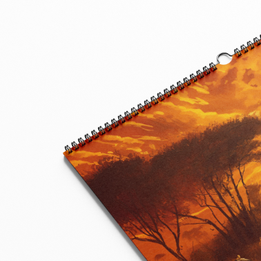 Close-up of the calendar cover featuring a vivid orange sunset with silhouetted acacia trees, spiral-bound with visible hanging hole.