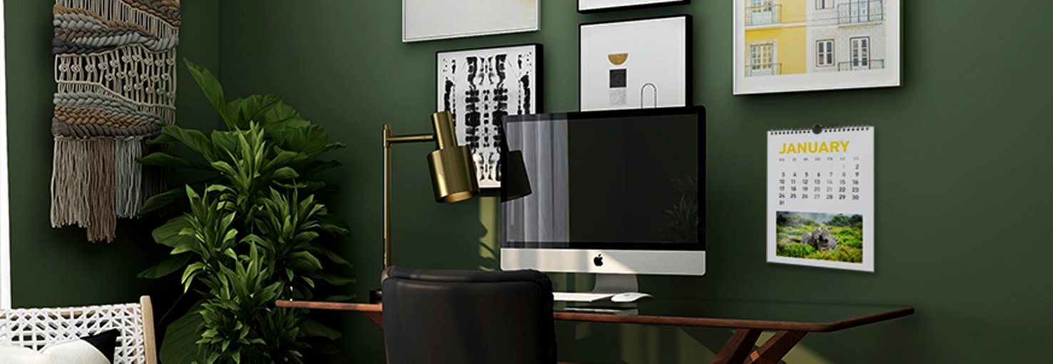 A home-office space with a wire-o calendar on a dark green wall.